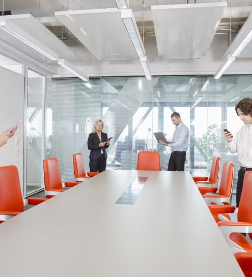 People using digital devices in conference room